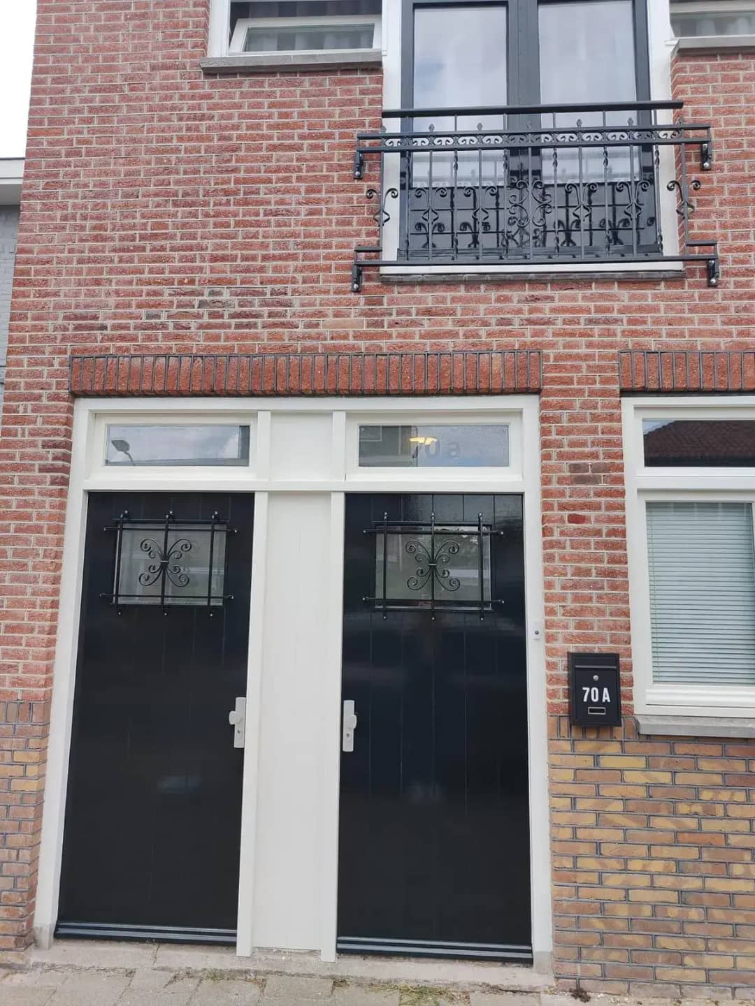 Stalen frans balkon hekwerk voor openslaande deuren vanaf straat kant gezien